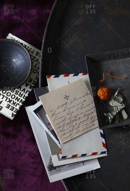Collection of letter and photos on black metal tray with Eiffel tower key chain on crushed purple velvet fabric