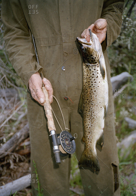 Midsection of a man holding a fishing pole and a fish