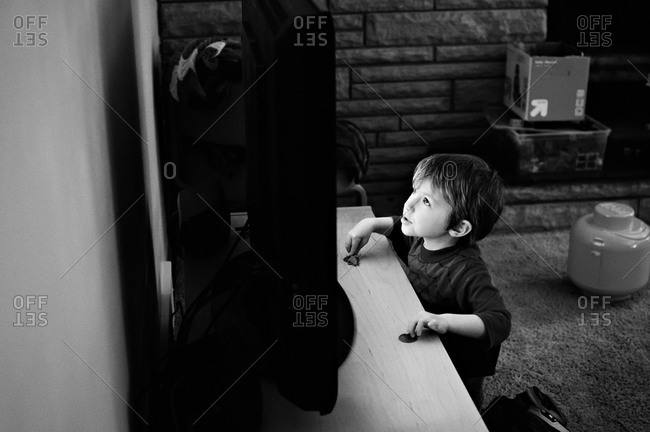 Young boy looking up at tv screen with the glow on his face.