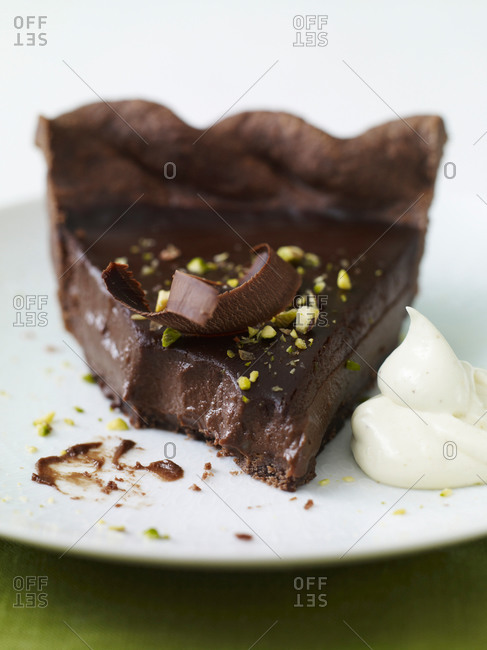 Triple chocolate tart with flake, whipped cream and pistachio on top.