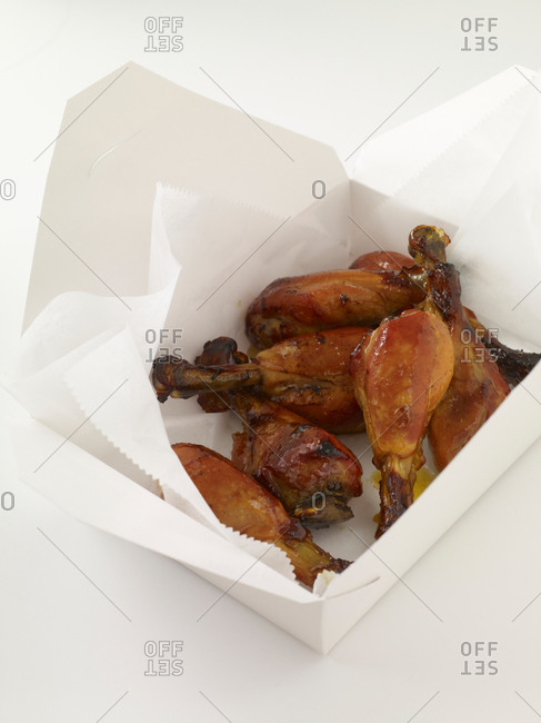 Roasted chicken legs in paper box.