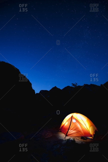 A tent glows by headlamp under a starry sky in Teton National Park, WY