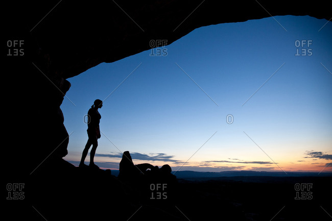 Female hiker overlooks the Turret Arch at sunset in Arches National Park near Moab Utah