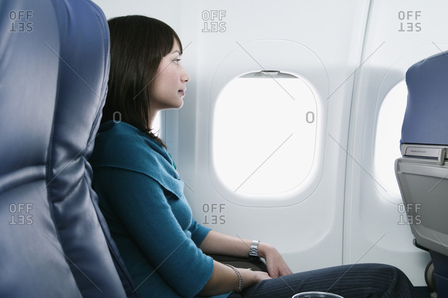 Young woman sitting in window seat on airplane