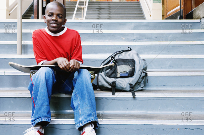 Portrait of boy with skateboard on school stairs
