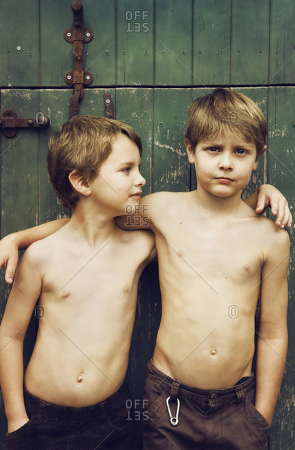Two young brothers with arms around each other next to barn