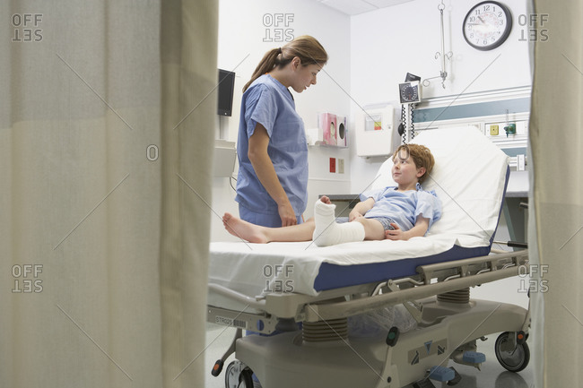 Nurse talking to boy with broken leg in hospital bed