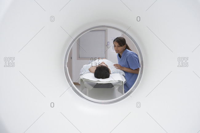 Indian nurse comforting patient entering MRI scanner