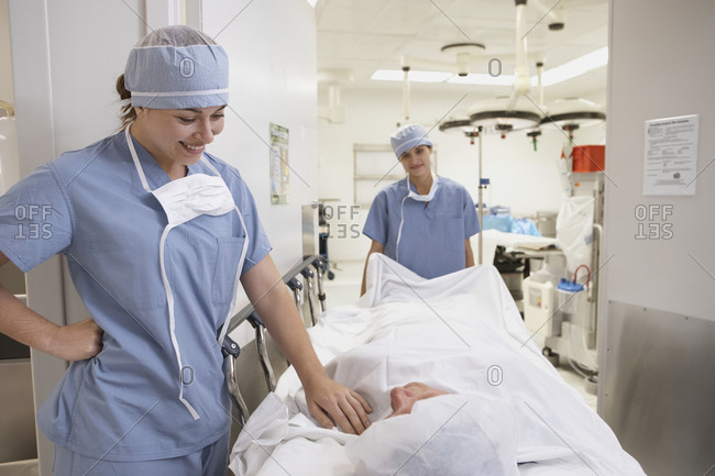 Hispanic female doctor smiling at patient being wheeled into operating room