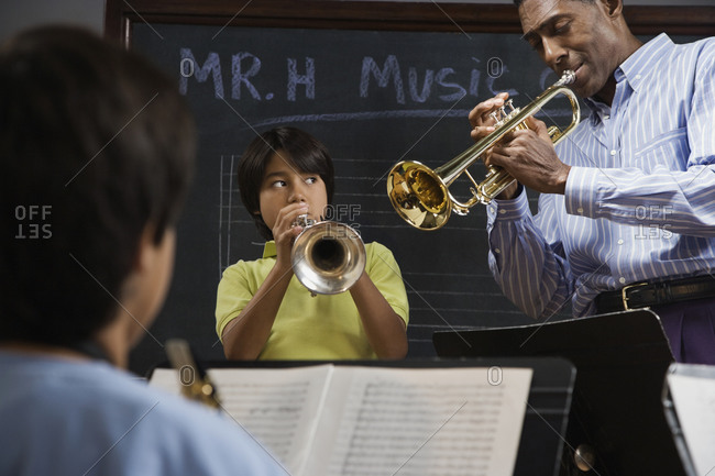 Multi-ethnic students learning to play trumpet with teacher