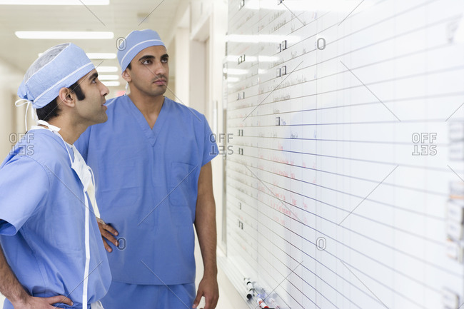 Asian surgeons looking at schedule in hospital