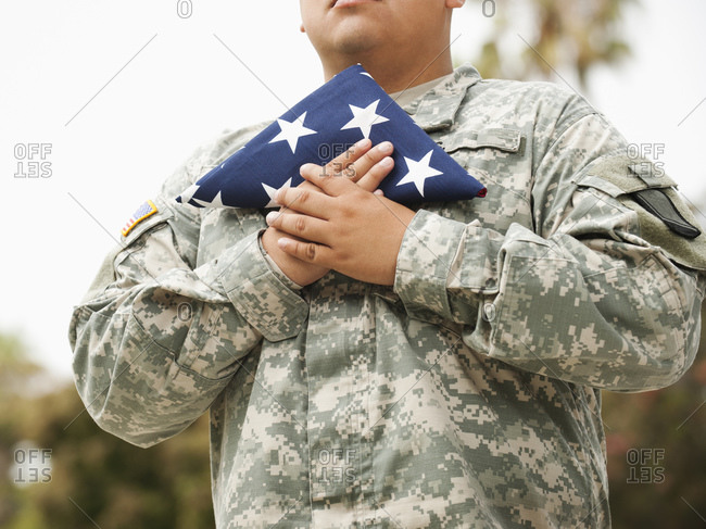 Hispanic soldier holding folded American flag
