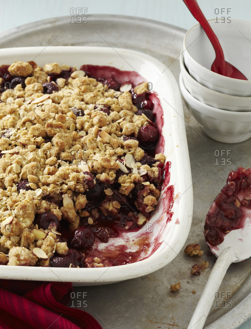Cherry crumble dessert with nuts in white dish.