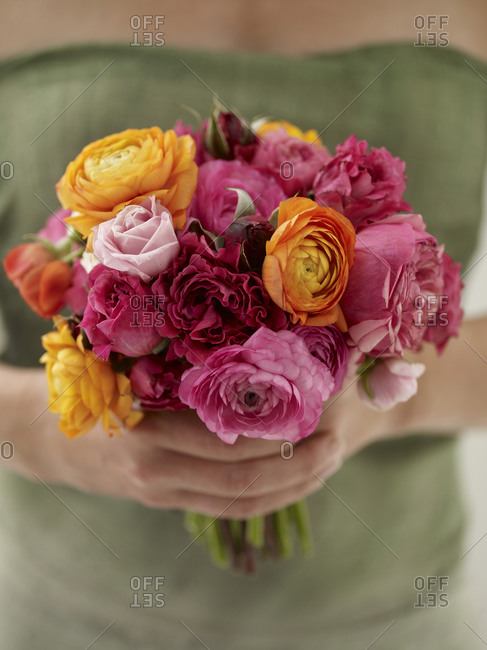 A woman holding a colorful cut flowers arranged into a bouquet.