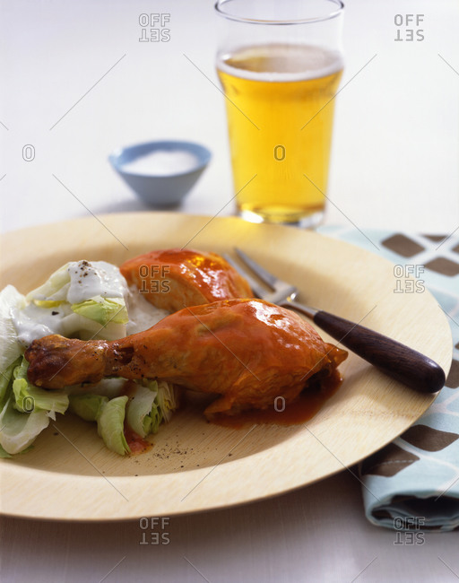 Plate of grilled chicken drumstick with salad and garlic sauce