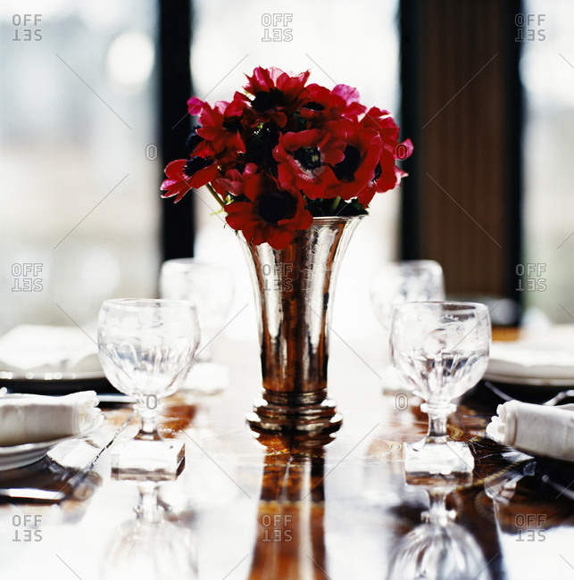 Red anemones in a vase on a set table