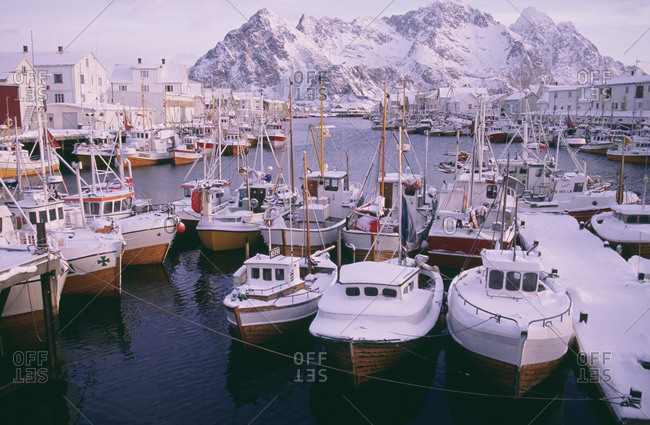 Boats moored in harbor with snow-covered mountains in background