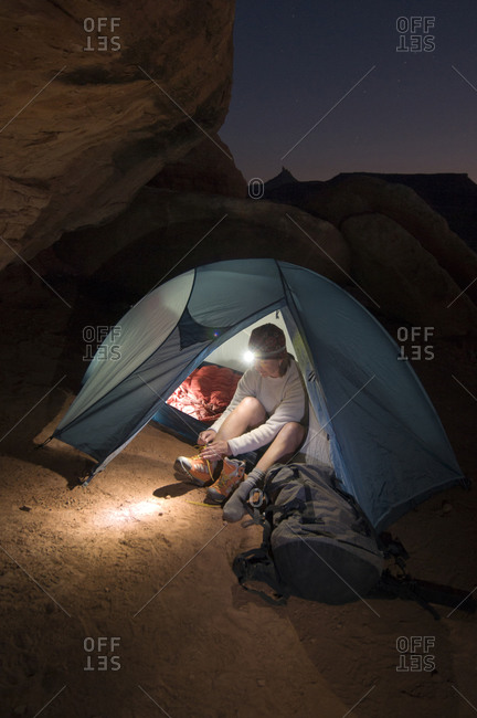 A woman camping in a tent with a headlamp in Indian Creek Canyon, Monticello, Utah.