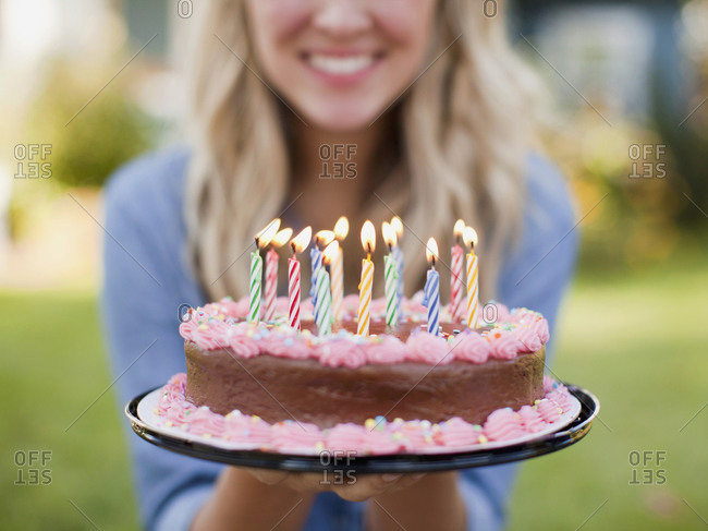 Mid-section of young woman holding a birthday cake