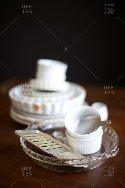 White vintage stacked dishes and graters on a wooden surface