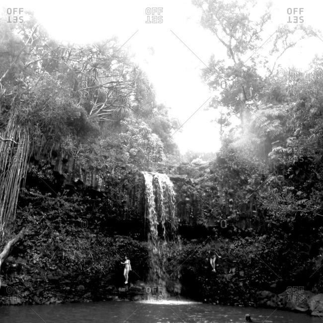 A black & white image of two girls swimming at a waterfall in Maui.