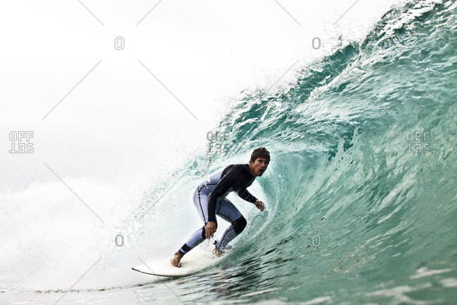 A male surfer crouches for a left tube while surfing at Zuma Beach in Malibu, California.