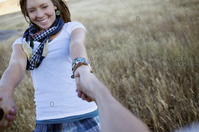 Young lady closes her eyes tight as she gets spun around by her boyfriend in an open field