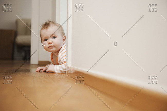 Baby Lying on Floor Peeking Around a Corner