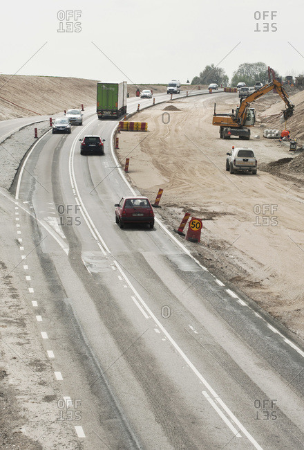 Vehicles moving on highway by construction site