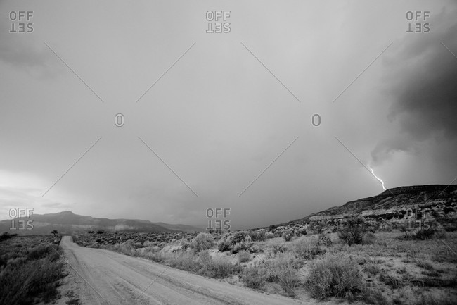 Lightning cracks in the distance as seen from a dirt road