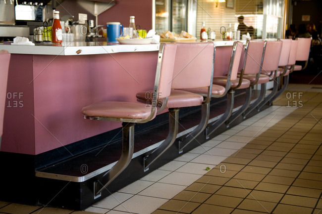 Classic pink chairs line a diner\'s empty counter