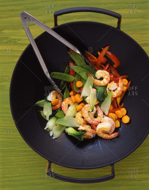 Wok with shrimp, carrots, snow peas, red peppers, pak choi and tongs