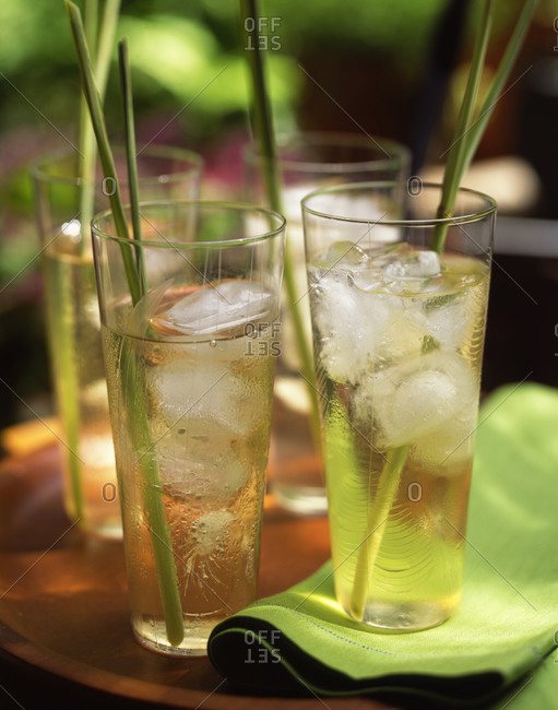 Icy lemonade served in tall glasses with grass garnish outdoors