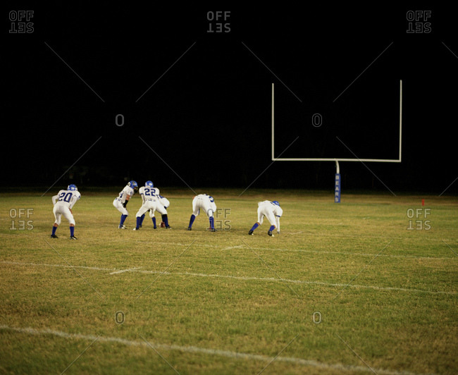 High School Football Players In Front Of A Goalpost At Night
