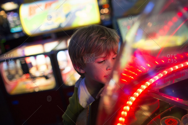 a young boy watches a game in an arcade