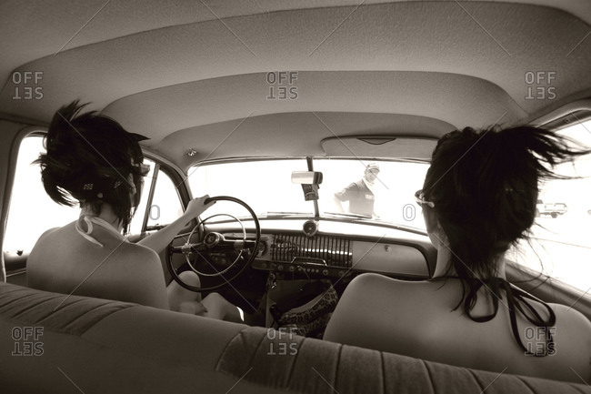 Two women sitting in vintage car wearing bikini