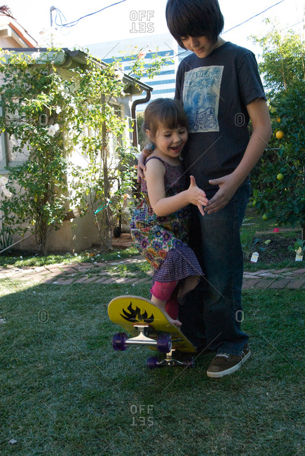 Boy Helping His Giggling Younger Sister On A Skateboard, Santa Monica