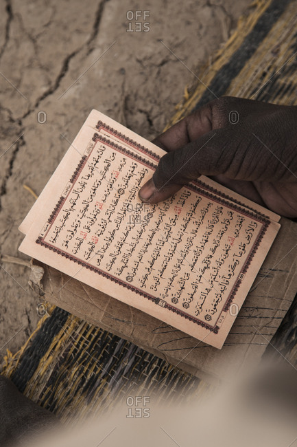 Hand holding pages with Arabic text