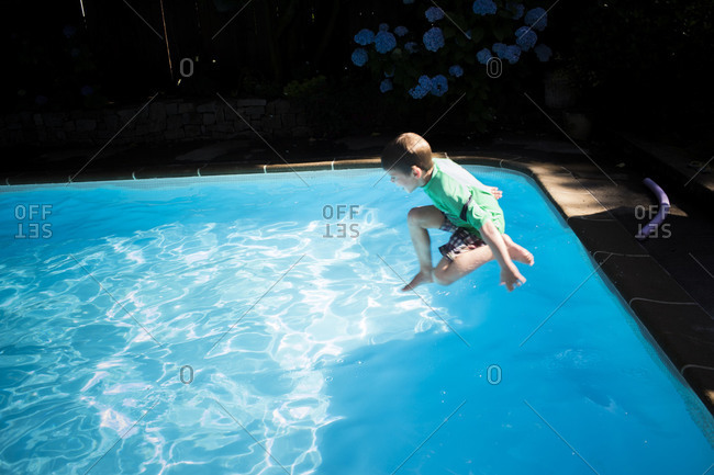 Boy jumping in the swimming pool wearing clothes