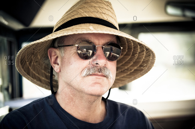 Portrait of Jim Roberts in sunglasses and straw hat on Lake San Antonio, California, USA