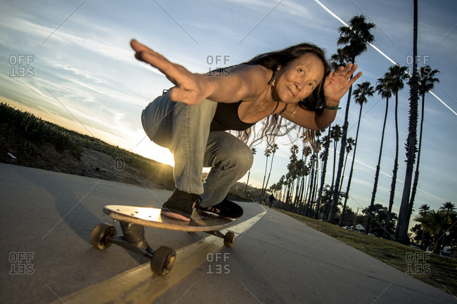Womani posing on skateboard in sunset
