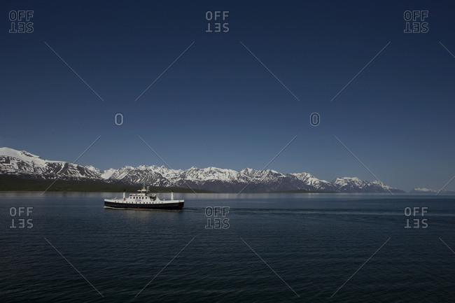 Ship Sailing Through Water With Mountain Peaks In The Background