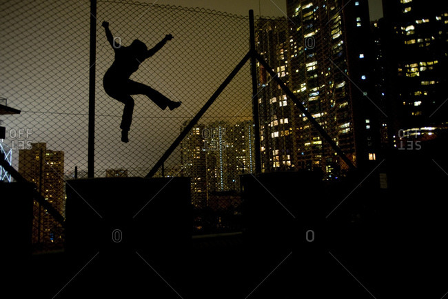 Woman climbing wire fence at night