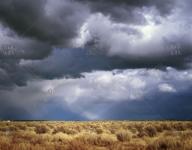 A house in a large, open field beneath a cloudy sky