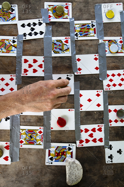 A man plays a game of checkers by using playing cards and beer bottle caps during a surf trip to Pascuales, Mexico.