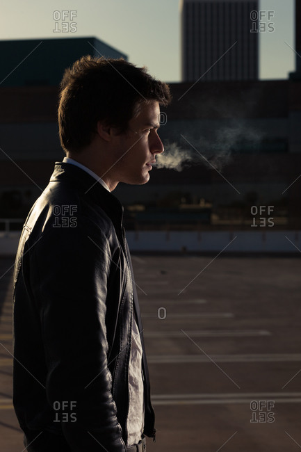 a portrait of a young man in a leather jacket smoking a cigarette