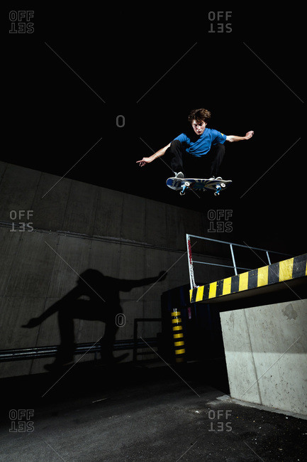 Germany, North Rhine-Westphalia, Duesseldorf, View of young skateboarder performing stunt at night
