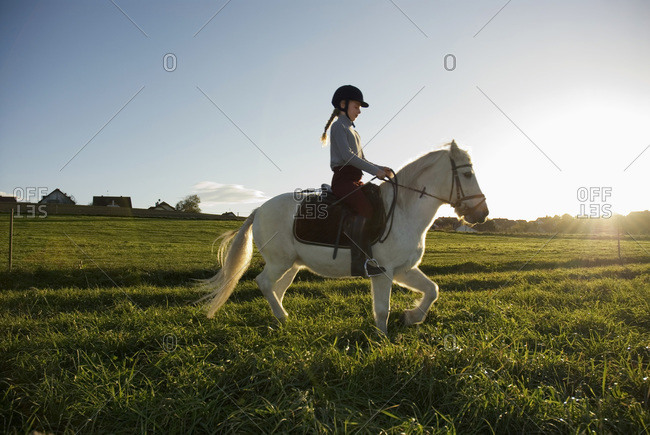 Girl (7-9) riding pony, side view