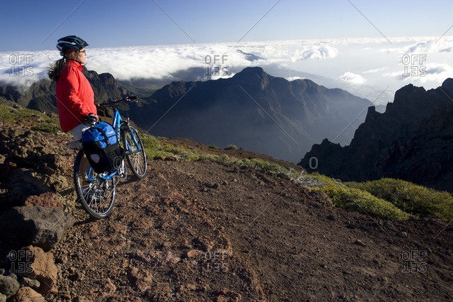 Spain, The Canary Islands, La Palma, Woman with mountain bike looking at mountain scenery