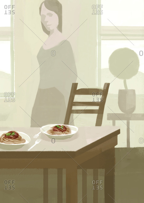 A simple home interior. A woman has just laid out two plates of spaghetti.